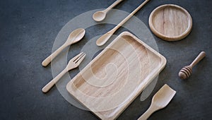 Wooden spoons and plate on dark gray gypsum on desktop