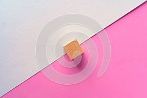 Wooden square block on pink and white background