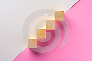 Wooden square block on pink and white background