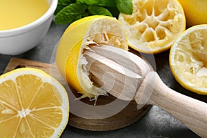 Wooden squeezer, lemons and mint on grey table, closeup
