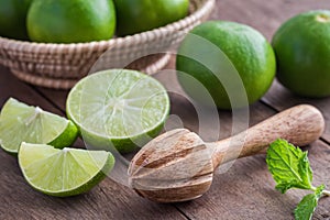 Wooden squeezer and lime on table