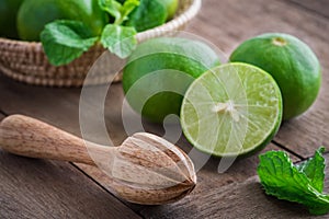 Wooden squeezer and lime on table