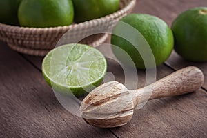 Wooden squeezer and lime on table