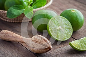 Wooden squeezer and lime on table
