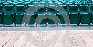 a wooden stage and rows of green chairs in the auditorium of a cinema or theater.