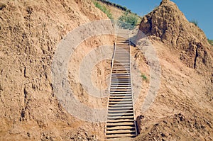 Wooden staircase attached to a clay rock on a sunny day
