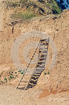 Wooden staircase attached to a clay rock on a sunny day