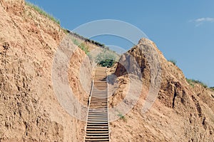 Wooden staircase attached to a clay rock on a sunny day