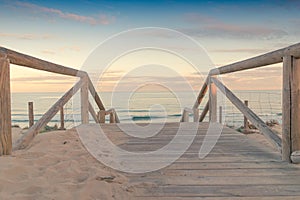 Wooden staircase and railing access to the beach sand at sunset