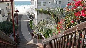 Wooden stairs, beach access in California USA. Coastal stairway, pacific ocean waves and palm trees.