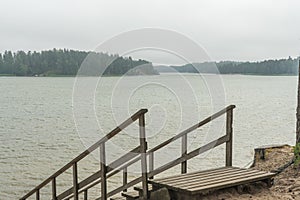 Wooden stairs to the seashore. Sandy beach, pine forest. Scandinavian nature. Finland. Porvoo