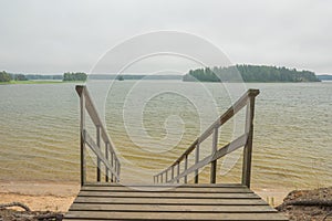 Wooden stairs to the seashore. Sandy beach, pine forest. Scandinavian nature. Finland. Porvoo
