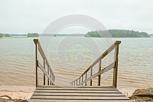 Wooden stairs to the seashore. Sandy beach, pine forest. Scandinavian nature. Finland. Porvoo
