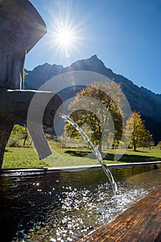 Wooden standpipe with fresh cold water, karwendel valley in autumn, bright sun