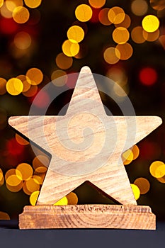 Wooden star for an award. Festive bokeh.