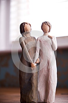 Wooden statue of two women holding hands, statue is on a black m