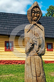 Wooden statue of villager in front of picturesque historical village Vlkolinec witjh wooden colorful cottages in Slovakia