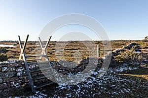 Wooden stile across an old dry stone wall