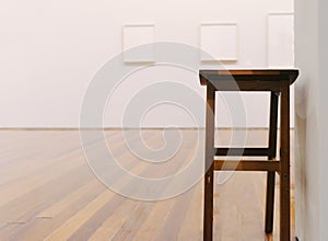 Wooden stool in empty museum looking room with paintings on wall