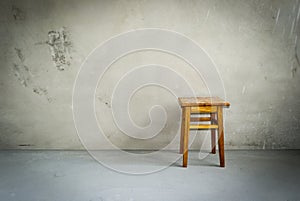Wooden stool in empty room. Chair on cement floor. Grunge interior