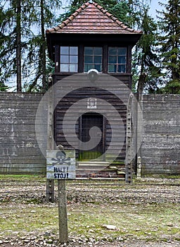 Wooden stop danger sign in front of a guard tower at the Auschwitz concentration camp