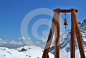 Wooden structure with bell in mountains in clear sunny day