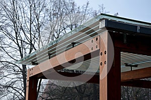 Wooden structure of the bus stop, the shelter of the gazebo pergola. the roof and walls are lined with glass. the glass is anchore