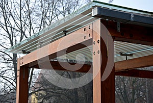 Wooden structure of the bus stop, the shelter of the gazebo pergola. the roof and walls are lined with glass. the glass is anchore