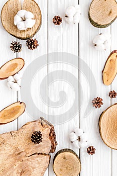 Wooden stumps, immortelle and pine cones frame for blog background top view space for text