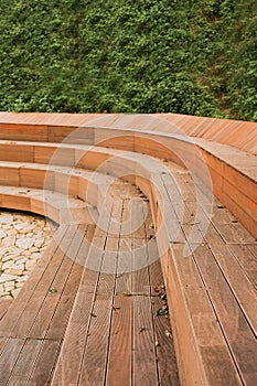 Wooden stylish modern city benches against green grassy wall, vertical, selective focus