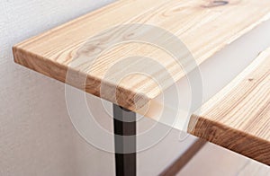 Wooden stylish table made of solid wood with epoxy resin on the background of the floor and wall. Close-up