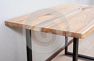 Wooden stylish table made of solid wood with epoxy resin on the background of the floor and wall. Close-up