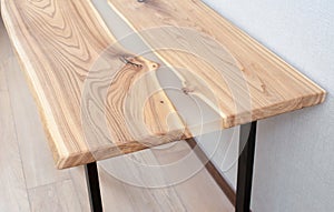 Wooden stylish table made of solid wood with epoxy resin on the background of the floor and wall. Close-up