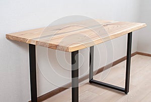 Wooden stylish table made of solid wood with epoxy resin on the background of the floor and wallWooden stylish table made of solid