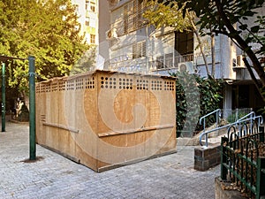 Wooden sukkah in a yard of a residential building in Israeli town during jewish holiday Sukkot