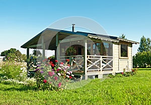 Wooden summer lodge with a flower bed