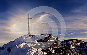 Wooden summit cross on the mountain peak with cloudy clear sky