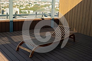 Wooden sun lounger on the roof of the penthouse overlooking the city. Soft selective focus