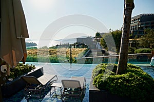 Wooden sunbeds and parasols on wooden deck nearby swimming pool in the evening. The outdoor recreation in luxury hotel.