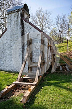 Wooden support scaffolding braces cracked wall of colonial cottage