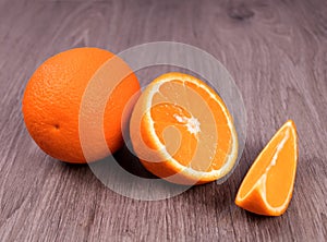 On the wooden surface are a whole orange and differently sliced â€‹â€‹oranges