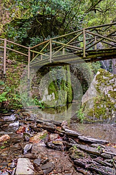 Wooden suspension bridge on hill, water and schist rocks of Barroca de DegraÃÂ­nhos river in Fraga de Pena, Arganil PORTUGAL photo