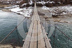 Wooden suspension bridge over a mountain river in a mountain village