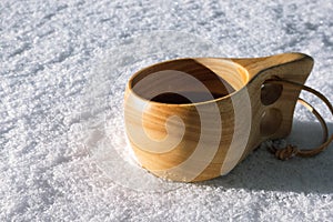 wooden Swedish Sami guksi drinking mug or cup in white snow for outdoor camping and hiking activities