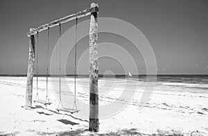 Wooden swing on the beach, monochrome. Swing with two seats on scenic seascape, black and white. Idyllic exotic resort.