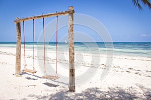 Wooden swing on the beach. Swing with two seats on scenic seascape. Idyllic exotic resort. Tropical paradise. Empty swing.