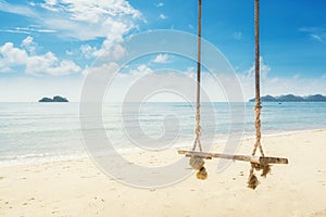 Wooden swing chair hanging on tree near beach at island in Phuket, Thailand. Summer Vacation Travel and Holiday concept.