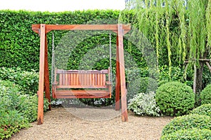 Wooden swing chair in natural green garden. Beautiful garden furniture