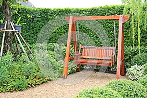 Wooden swing chair in natural green garden. Beautiful garden furniture