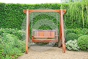 Wooden swing chair in natural green garden. Beautiful garden furniture